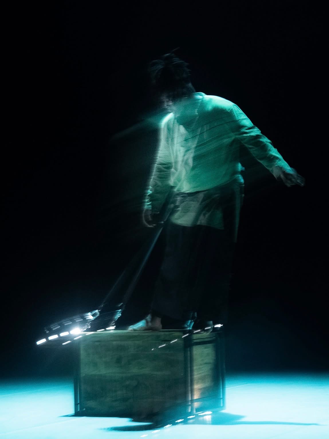 Solo sur scène, lumière bleu-vert, mouvement