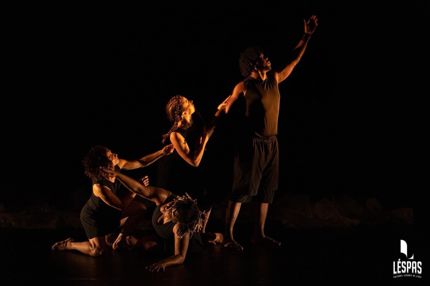 Trio sur scène, lumière chaude, fond sombre